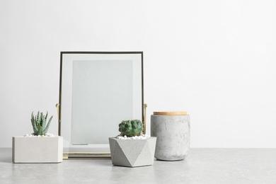 Photo of Blank frame and beautiful succulent plants on table against light background, space for design. Home decor