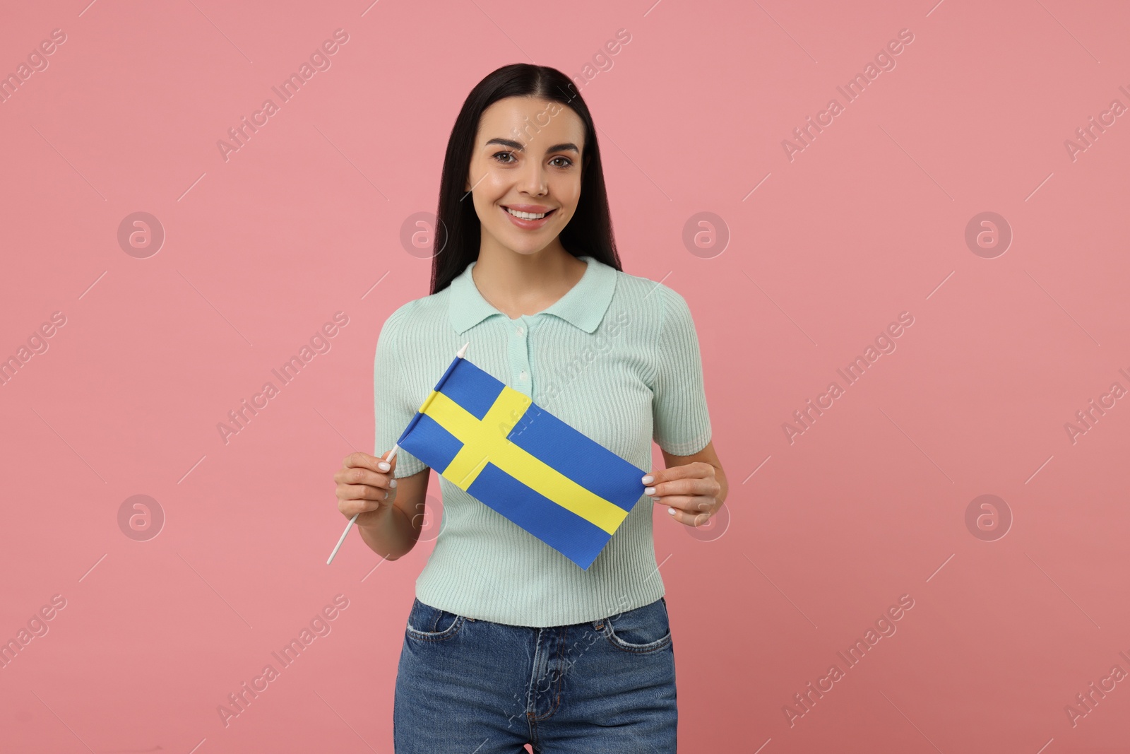 Photo of Happy young woman with flag of Sweden on pink background