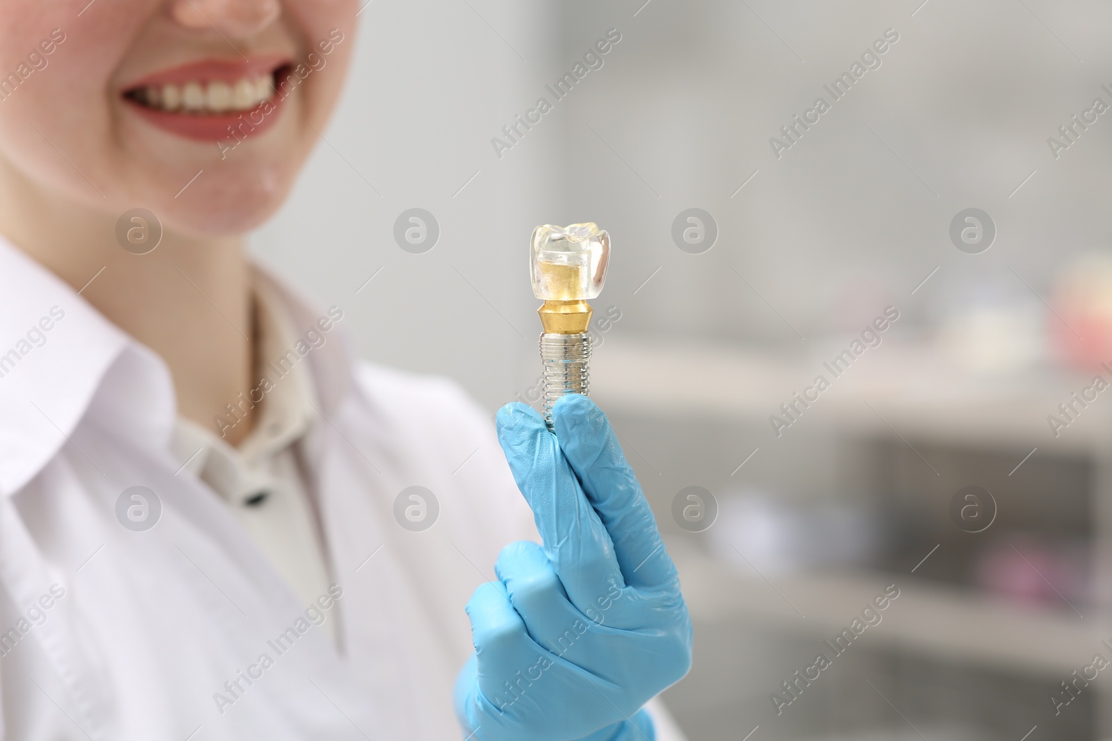 Photo of Dentist holding educational model of dental implant indoors, closeup. Space for text