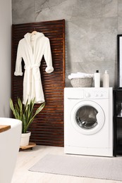 Photo of Stylish laundry room with modern washing machine. Interior design