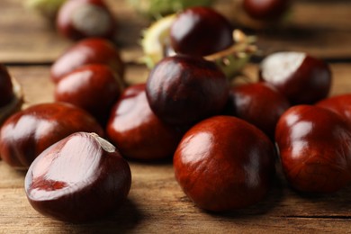 Photo of Many horse chestnuts on wooden table, closeup