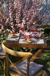 Photo of Delicious Belgian waffles with fresh strawberries and wine served on table in spring garden