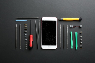 Photo of Flat lay composition with broken mobile phone and repair tools on color background