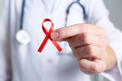 Photo of Doctor holding red awareness ribbon, closeup. World AIDS disease day