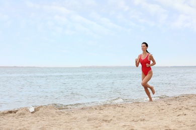 Photo of Beautiful female lifeguard running at sandy beach