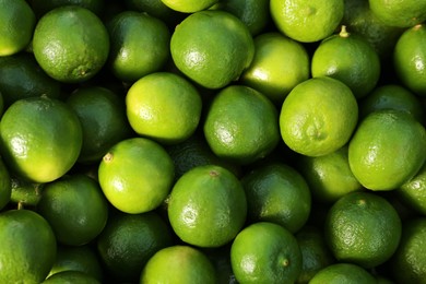 Photo of Fresh ripe green limes as background, top view