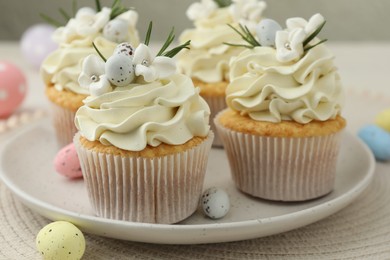 Photo of Tasty Easter cupcakes with vanilla cream and candies on table, closeup