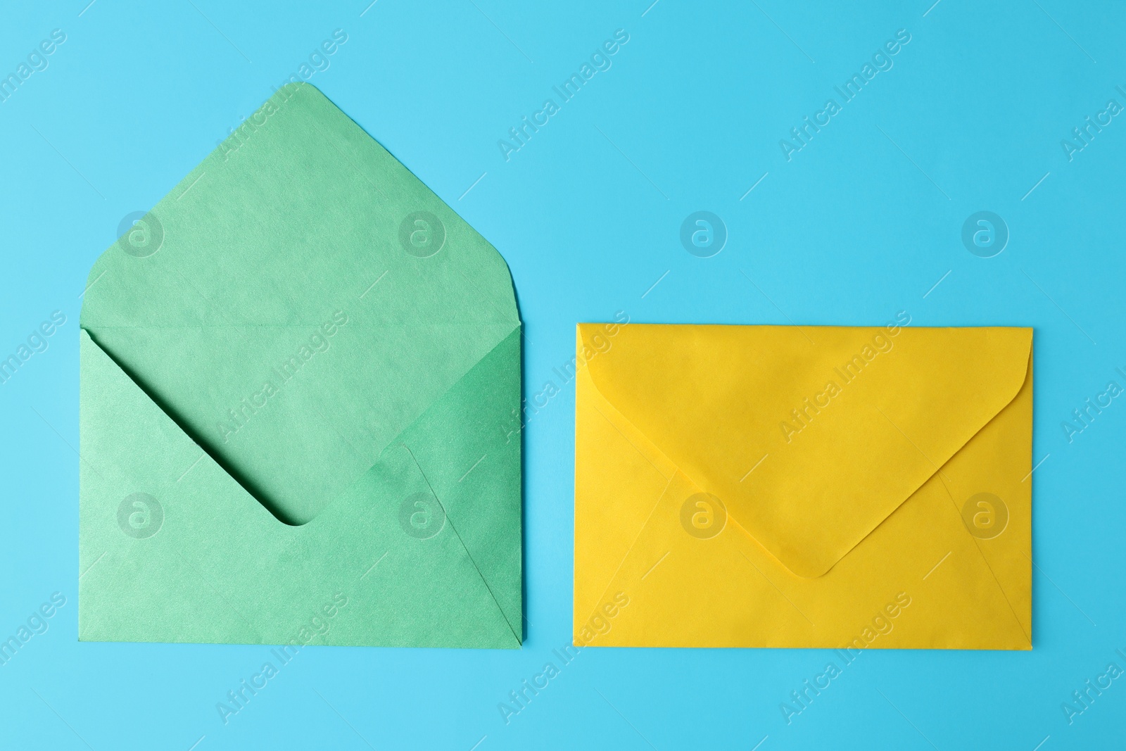 Photo of Colorful paper envelopes on light blue background, flat lay
