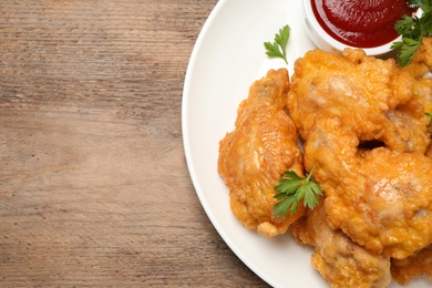 Photo of Tasty deep fried chicken pieces served on wooden table, top view. Space for text