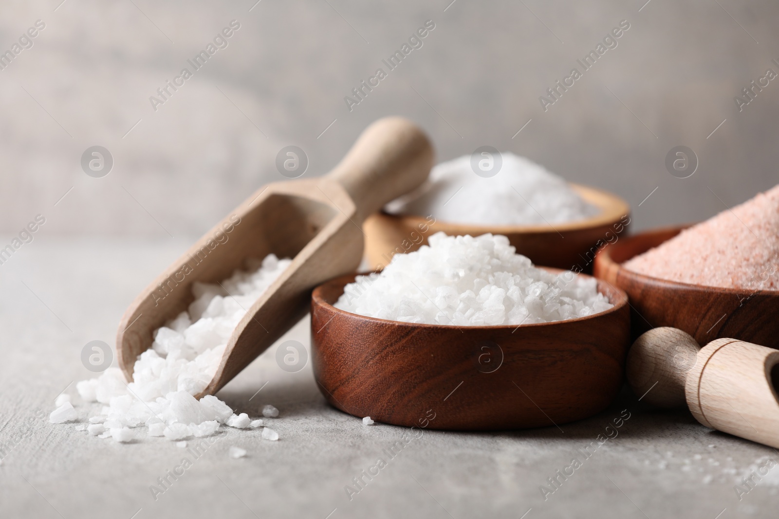 Photo of Different natural salt on grey table, closeup