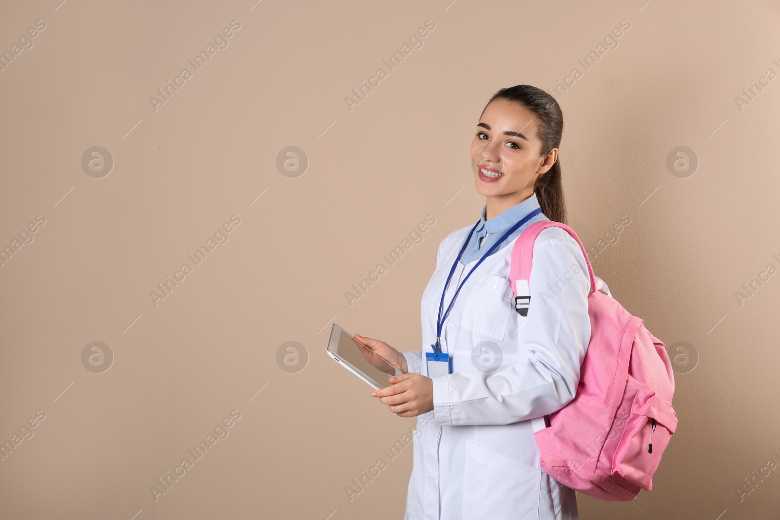 Photo of Young medical student with tablet and backpack on color background. Space for text