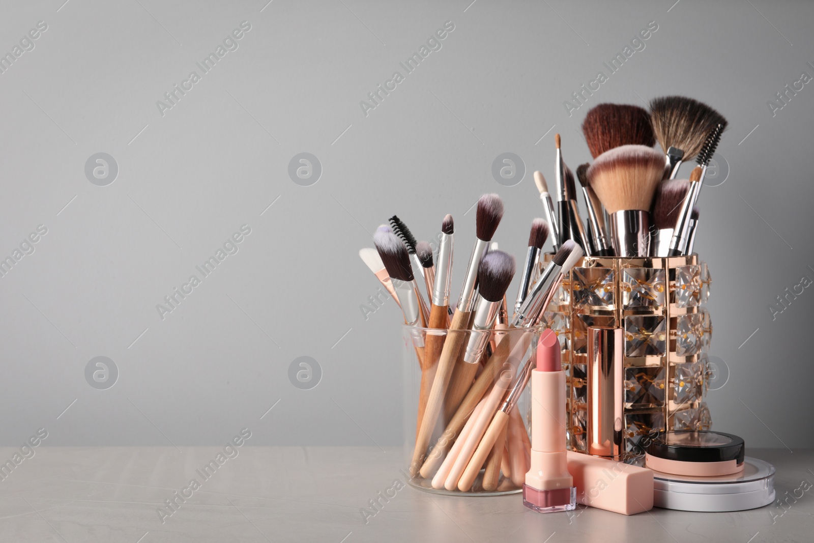 Photo of Set of professional brushes and makeup products on table against grey background, space for text