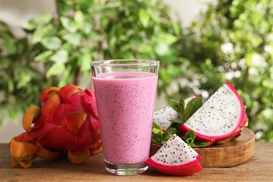 Photo of Delicious pitahaya smoothie and fresh fruits on wooden table