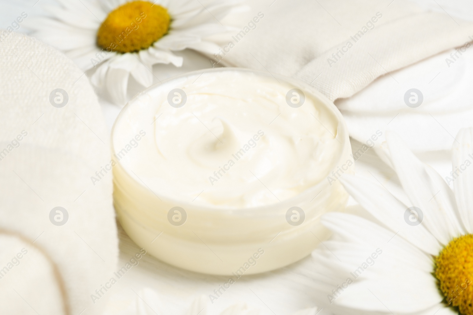 Photo of Composition with chamomile flowers and cosmetic product on white wooden table, closeup