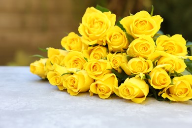 Beautiful bouquet of yellow roses on light table outdoors