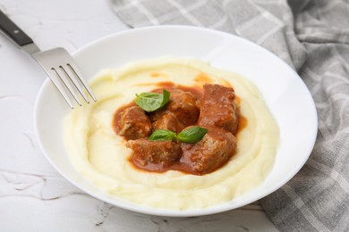 Delicious goulash served with mashed potato on white textured table, closeup