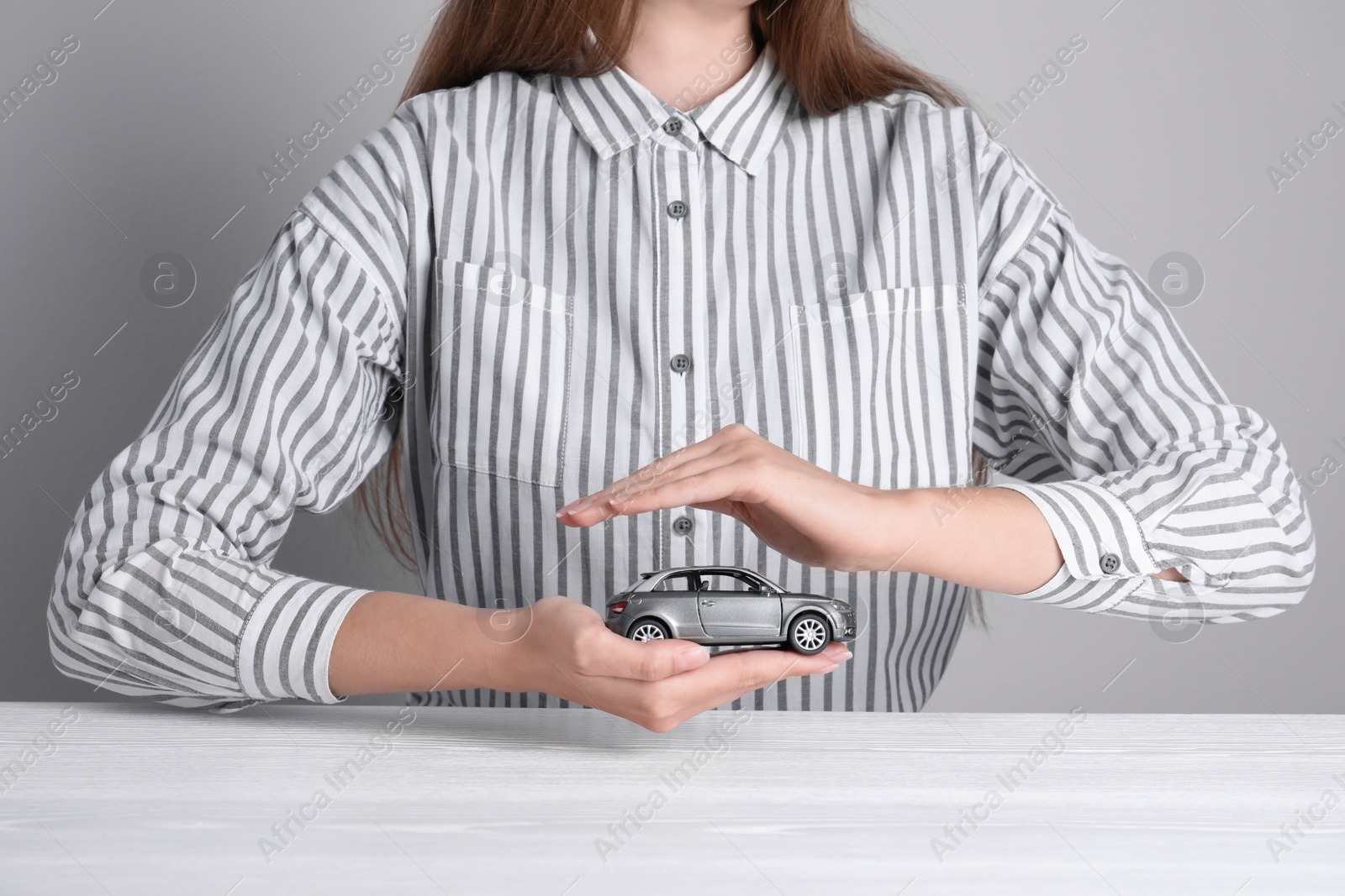 Photo of Insurance agent covering toy car at table, closeup