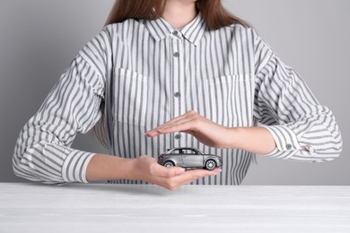 Insurance agent covering toy car at table, closeup