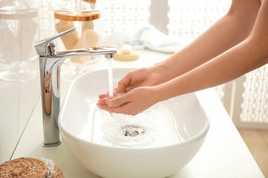 Photo of Woman washing hands indoors, closeup. Bathroom interior