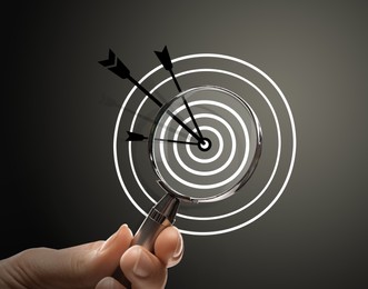 Image of Woman holding magnifying glass on dark background, closeup. Illustration of target and arrow