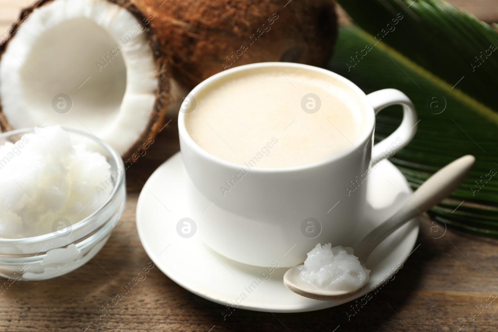 Photo of Delicious coffee with organic coconut oil on wooden table