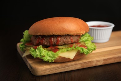Photo of Tasty burger with patty, lettuce and cheese on wooden table, closeup