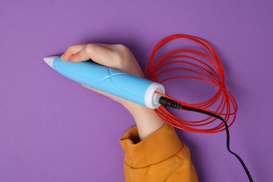 Photo of Boy drawing with stylish 3D pen on purple background, top view