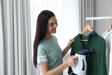 Woman steaming shirt on hanger at home