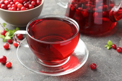 Photo of Tasty hot cranberry tea in glass cup and fresh berries on light grey textured table