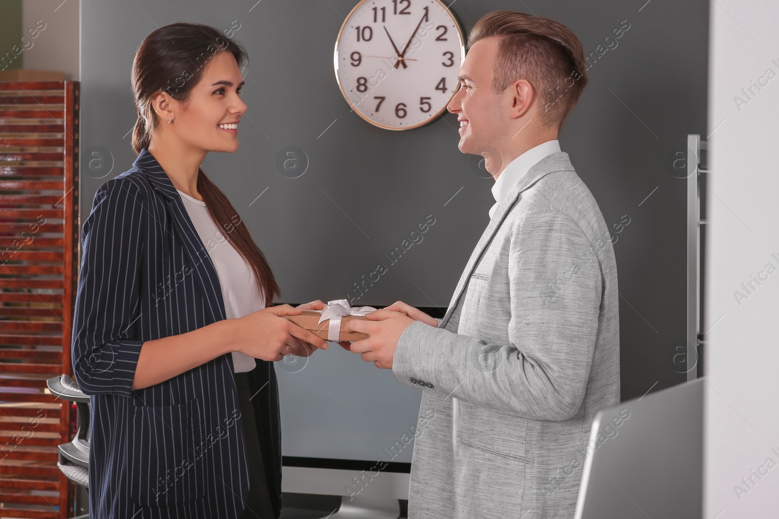 Photo of Woman presenting gift to her colleague in office