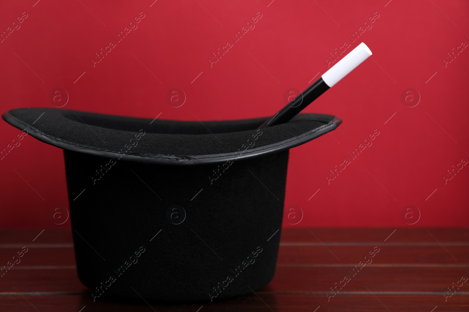 Photo of Black top hat and wand on wooden table, space for text. Magician equipment