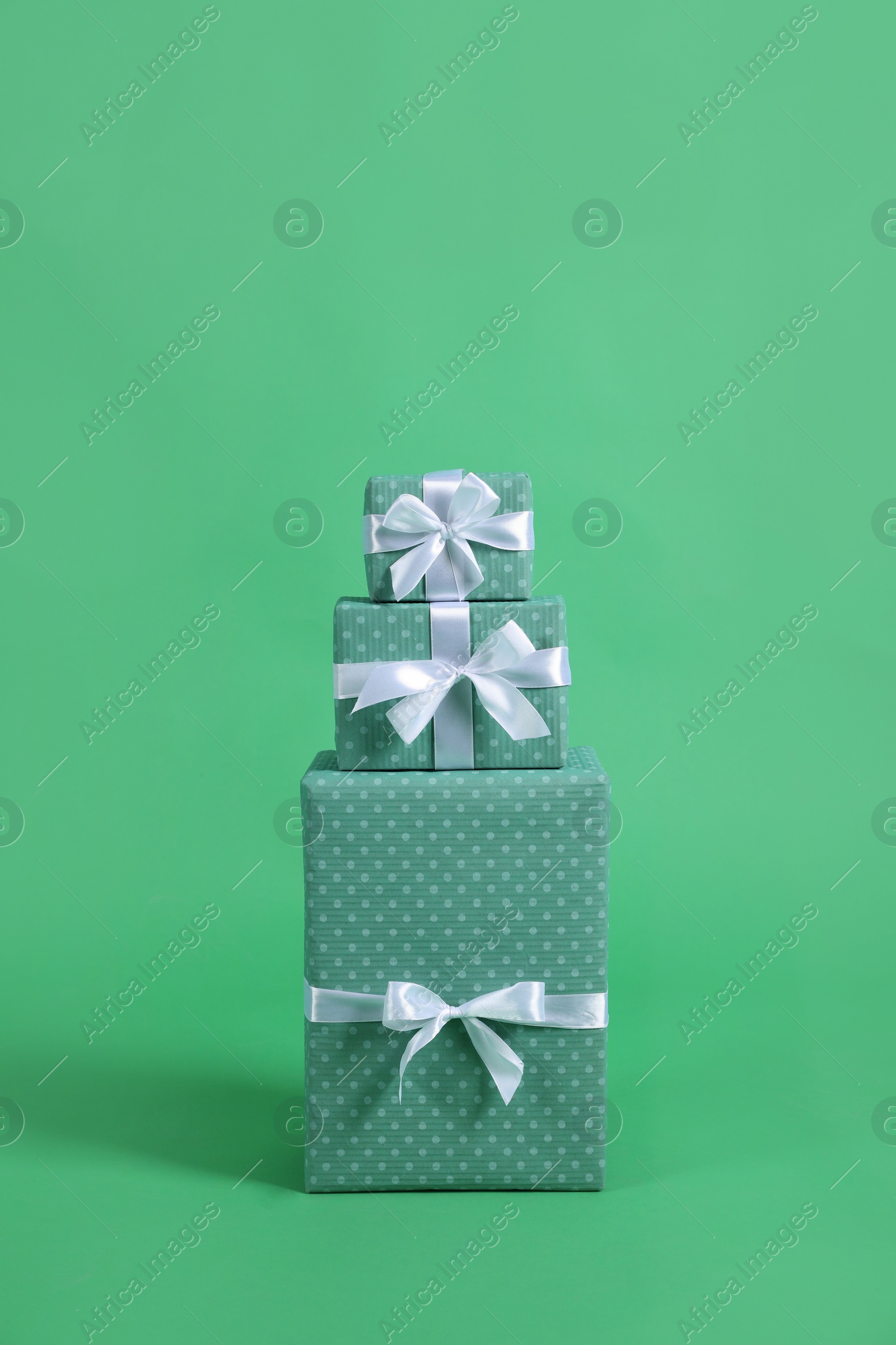 Photo of Stack of beautifully wrapped gift boxes on green background