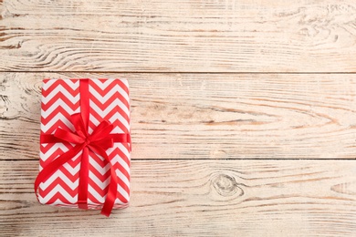 Elegant gift box with bow on wooden background, top view