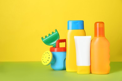 Different suntan products and plastic beach toys on color background. Space for text