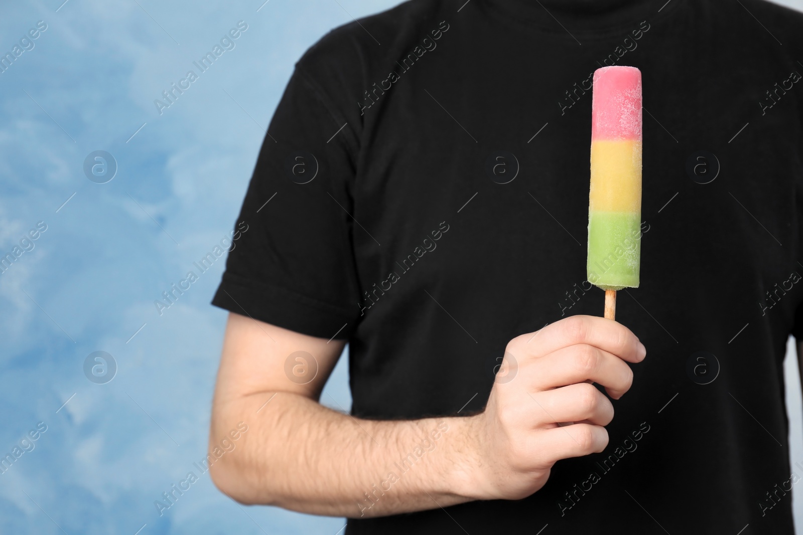 Photo of Man holding yummy ice cream on color background. Focus on hand