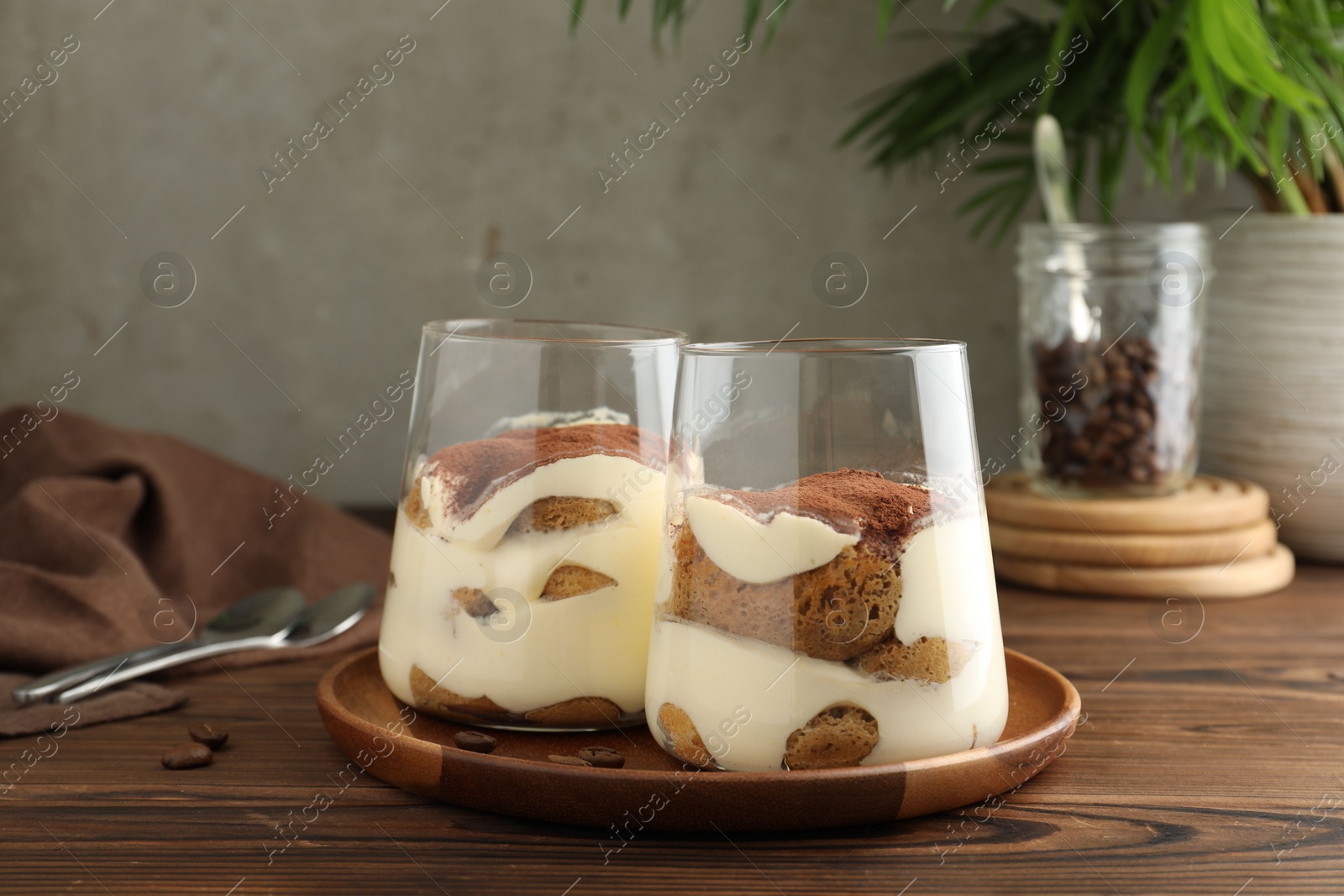 Photo of Delicious tiramisu in glasses on wooden table