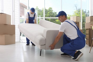 Photo of Moving service employees carrying sofa in room