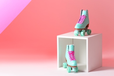 Photo of Pair of vintage roller skates and storage cube on color background. Space for text