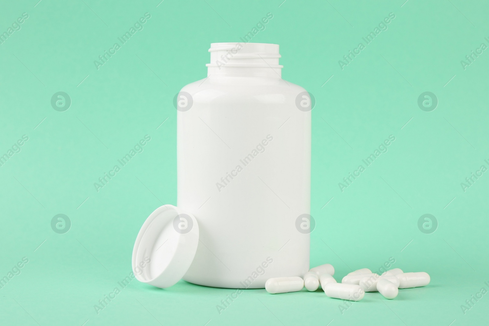 Photo of Blank white jar with vitamin capsules on turquoise background, space for text