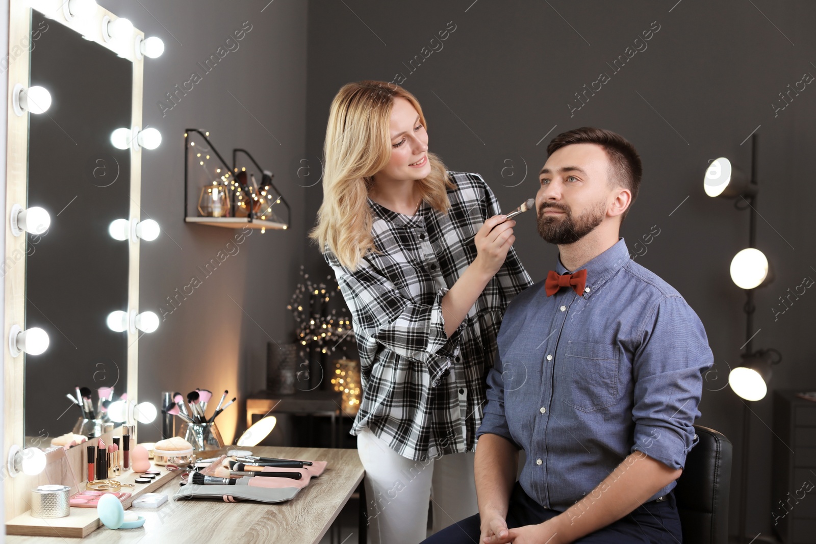 Photo of Professional makeup artist working with client in dressing room