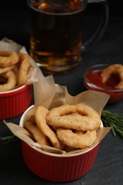 Photo of Fried onion rings served on black table