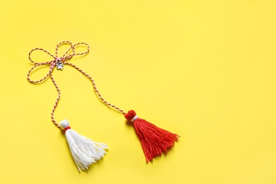 Photo of Traditional martisor on yellow background, space for text. Beginning of spring celebration