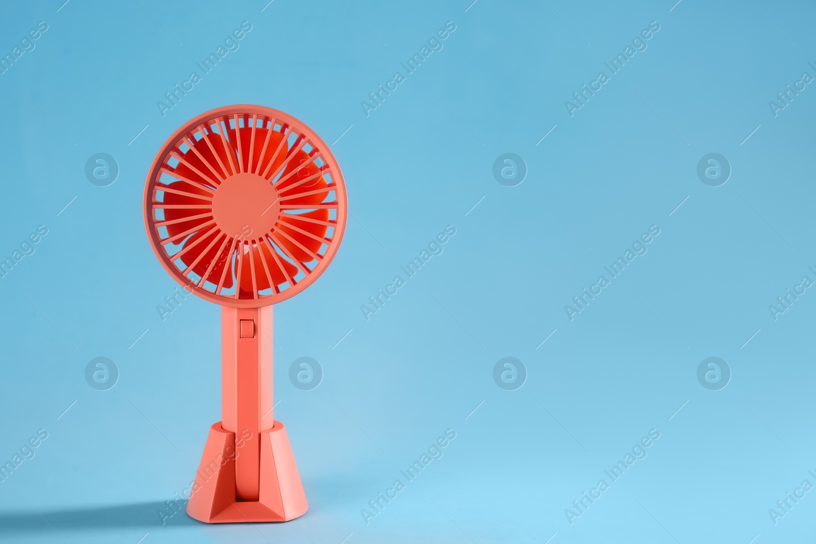 Photo of Modern electric fan on light blue background. Space for text