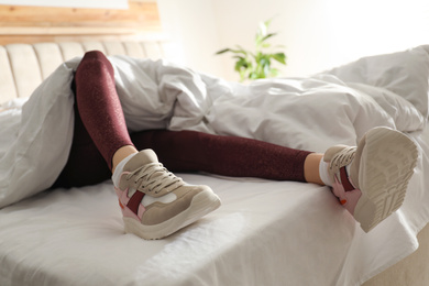 Photo of Lazy young woman sleeping on bed instead of morning training, closeup