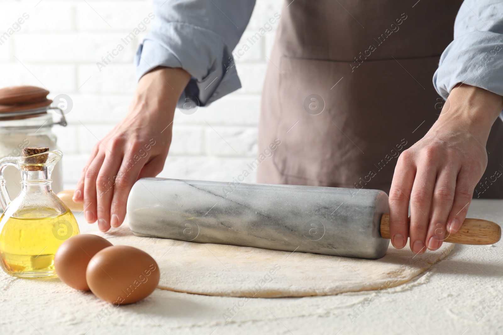 Photo of Woman rolling raw dough at table, closeup