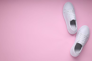 Photo of Pair of stylish white sneakers on pink background, top view. Space for text