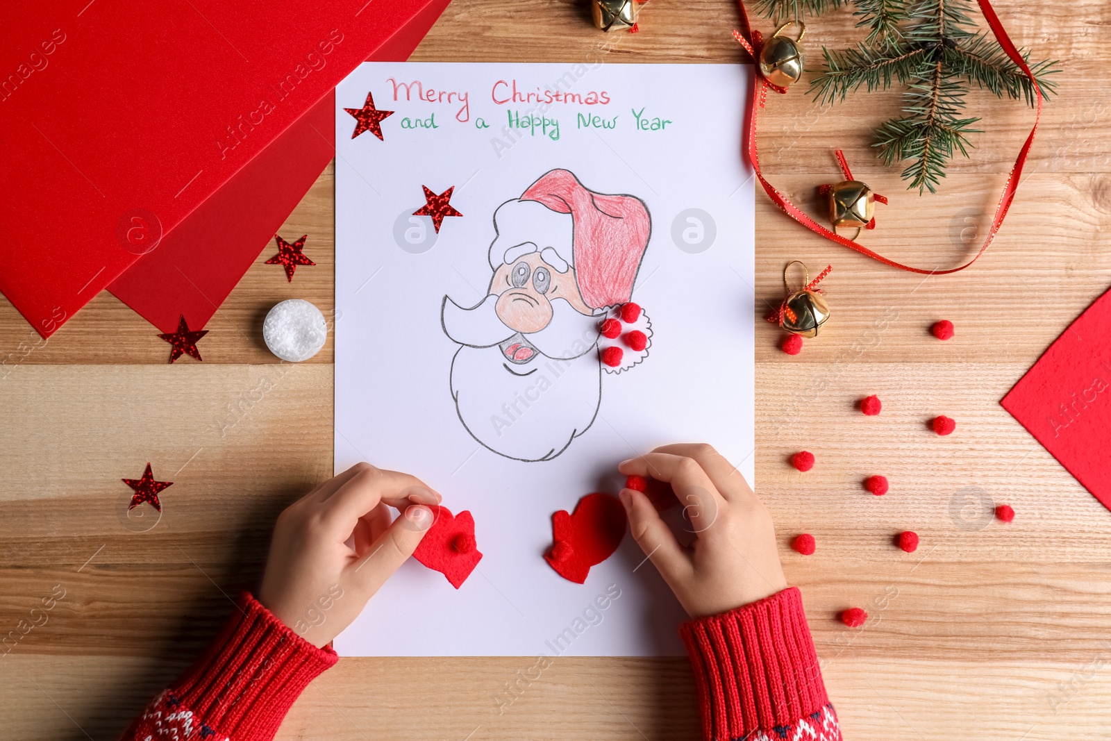 Photo of Little child making Christmas card at wooden table, top view