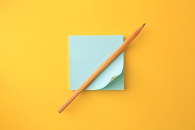 Photo of Blank paper note and pencil on orange background, top view