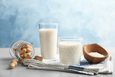 Glasses with coconut and peanut milk on grey table