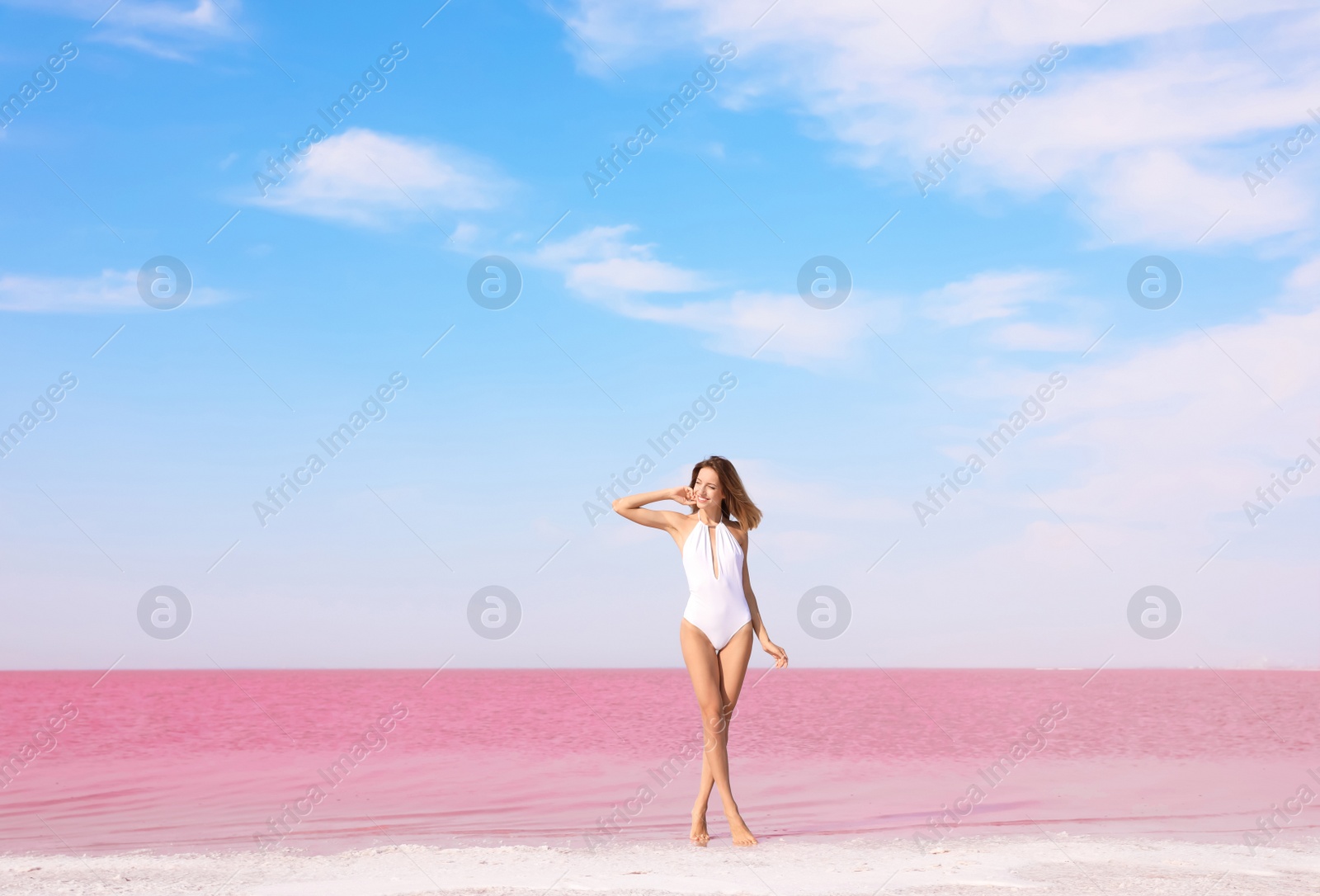 Photo of Beautiful woman in swimsuit posing near pink lake on sunny day